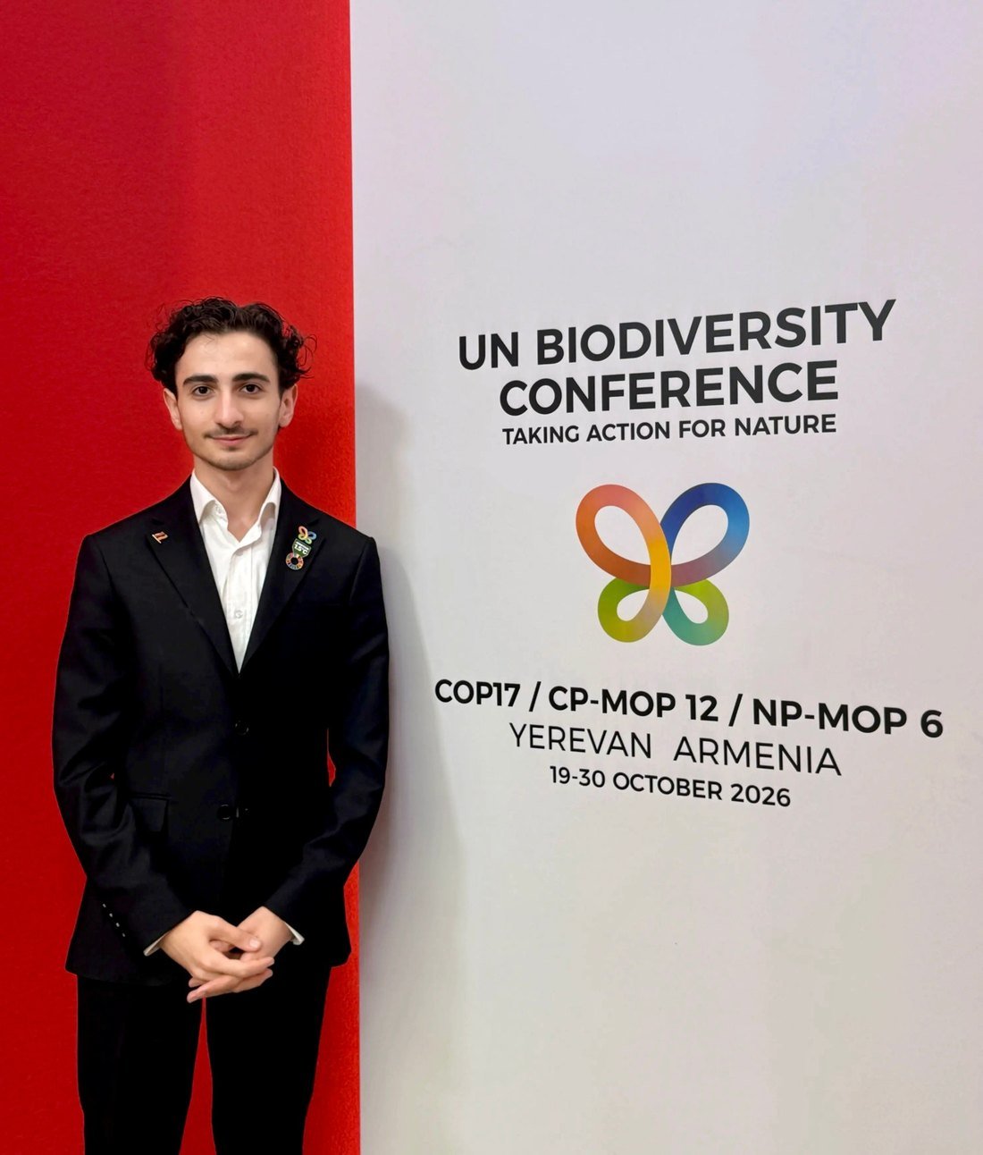 Narek Ohanyan in a dark suit standing beside the UN Biodiversity Conference wall in Yerevan, with the COP17 butterfly logo and the dates 19 to 30 October 2026