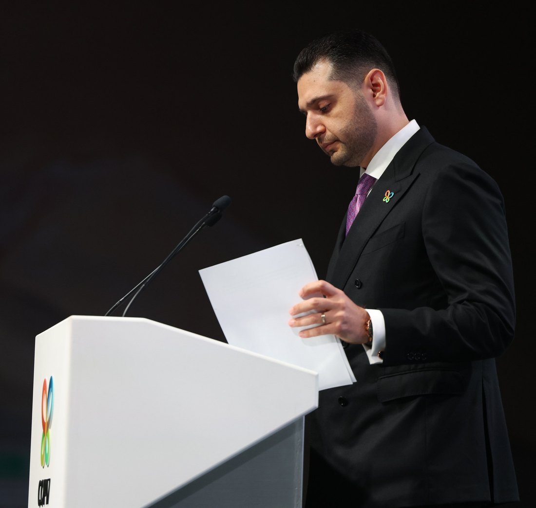Hambardzum Matevosyan, the COP17 President, at a white podium with the COP17 butterfly logo, looking down at his papers